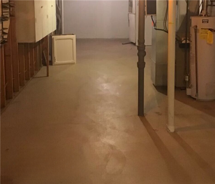 Empty basement with water heater and high ceiling.