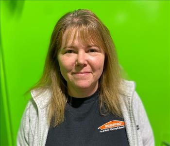 Employee in front of green wall in black SERVPRO shirt 