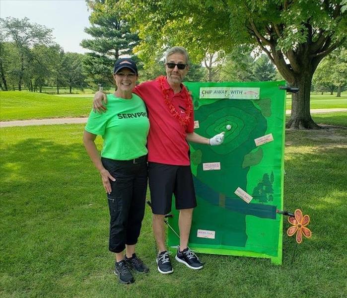 SERVPRO employee with golfer next to our golf game at the hole