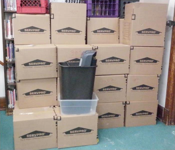 Several cardboard boxes stacked together against a wall with the SERVPRO logo on it.
