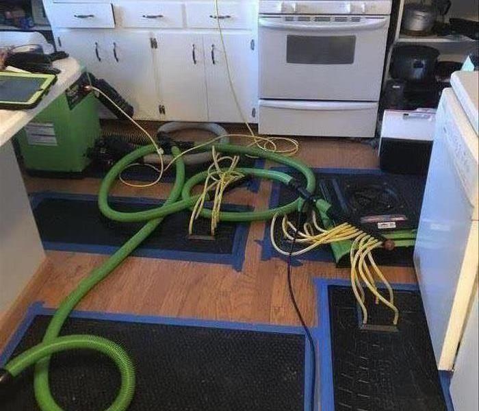 large green equipment with two attachments, hoses and a mat suction for the hardwood flooring.