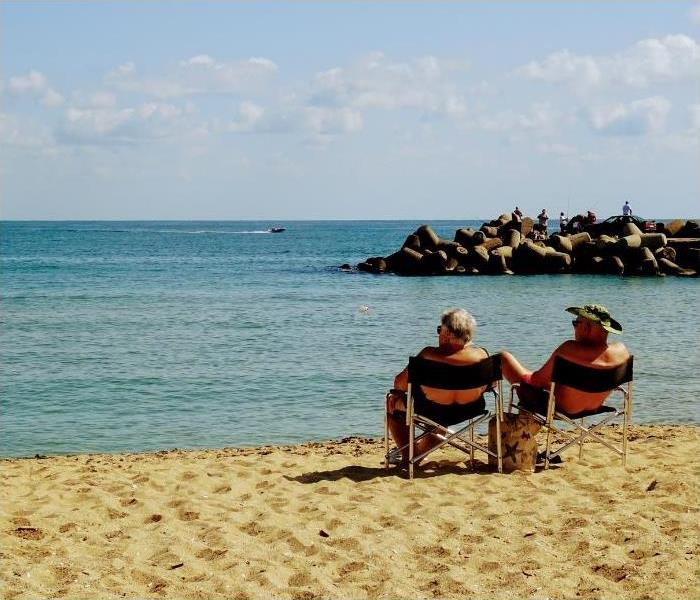 2 senior couples sitting on a beach share on the shore looking at the sea.