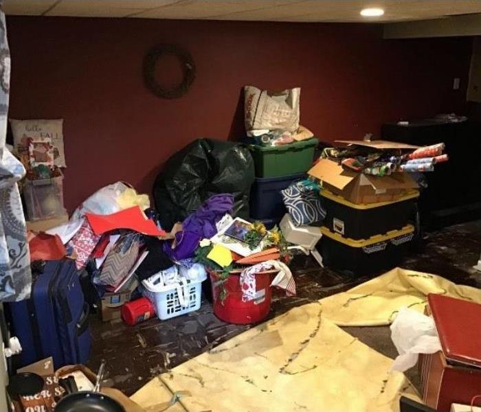 Cluttered basement with water on the floor.