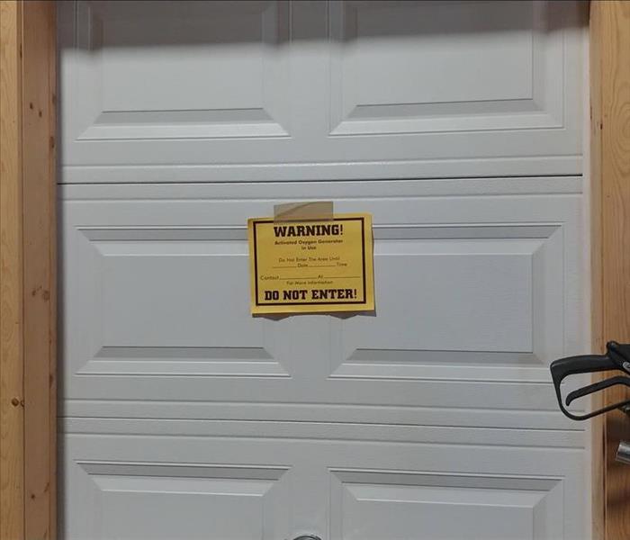Yellow warning Label with bold text on an overhead door.