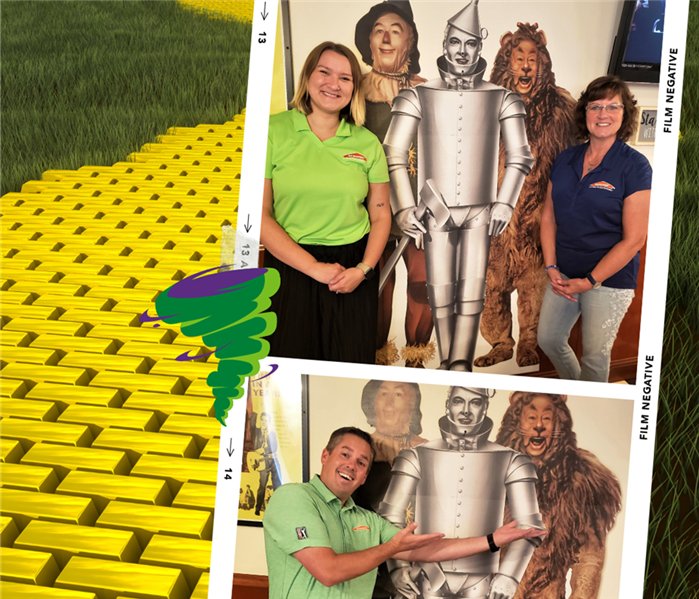 employees next to wizard of oz wall with yellow brick in backround