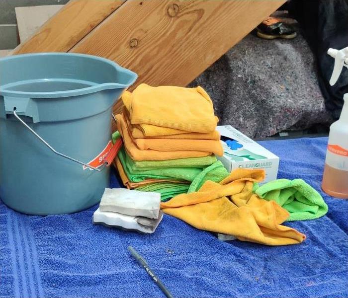  A picture containing a bucket, microfiber cloths, gloves and a spray bottle with an orange cleaner.